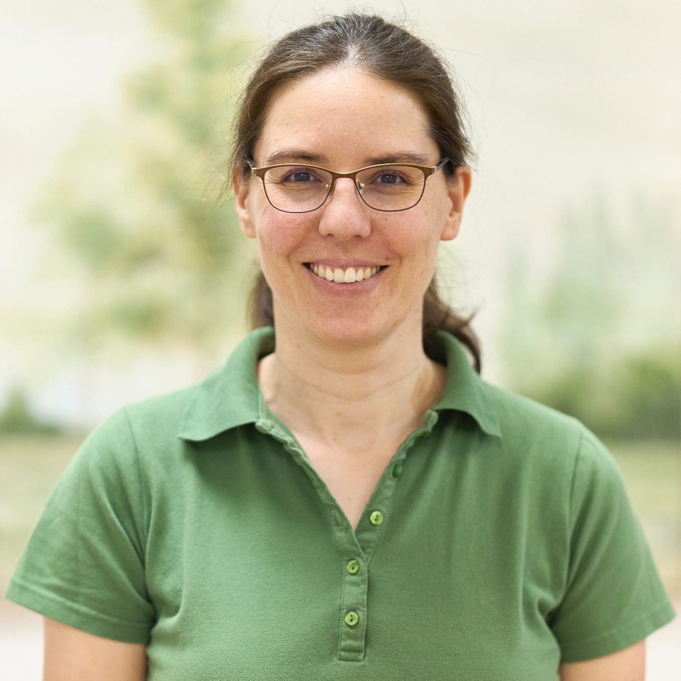 Andrea Kuttin. Braune Haare, braune Brille, grünes Poloshirt, lächelt freundlich.
